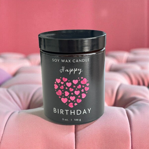Black soy wax candle with pink heart design on a pink cushion