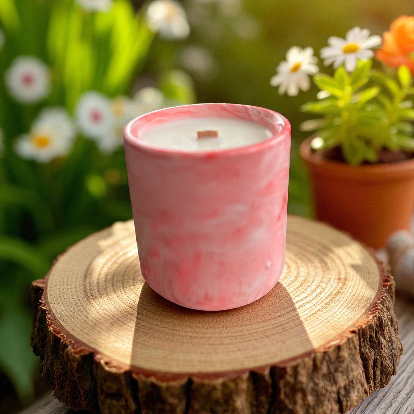 Pink candle in a mottled pattern on a wooden stump with a garden background