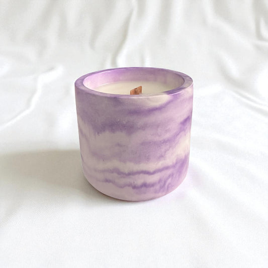 Candle in a purple and white marbled container on a white background